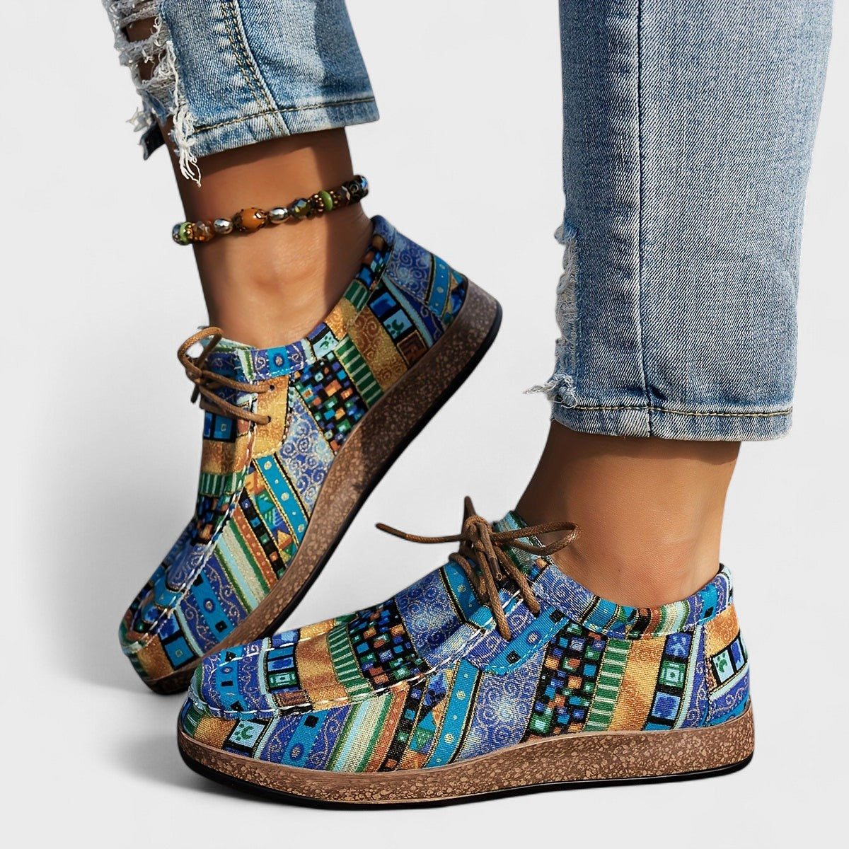 Colorful patterned shoes worn with rolled-up jeans on a light background