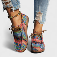 Colorful patterned shoes worn with ripped jeans on a plain background